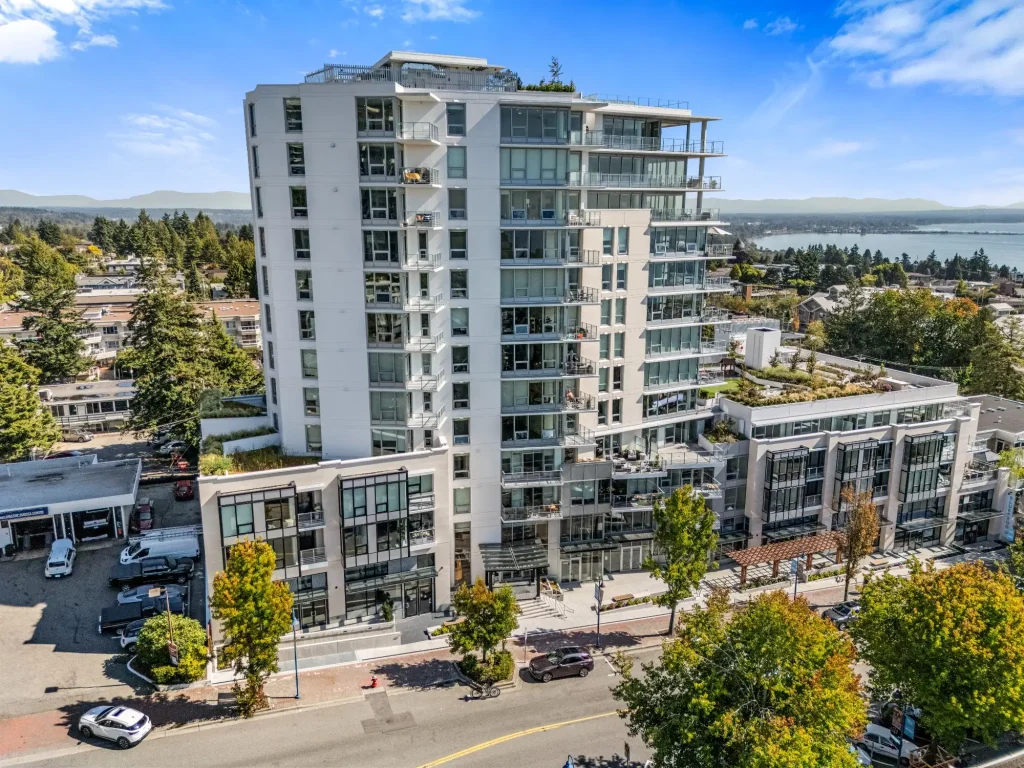 Aerial photo of a white high-rise and the streets around it, with the ocean behind